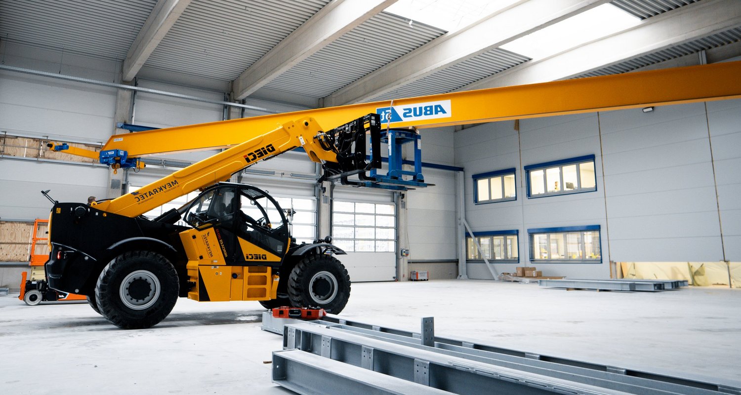 Teleskoplader bei der Montage eines Industriekrans in einer Halle