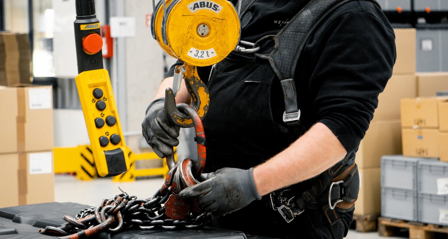 Servicetechniker prüft Lasthaken und Kettengehänge an einem Industriekran